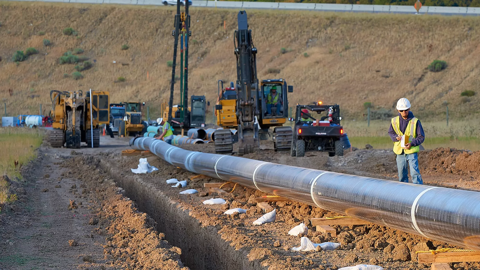 crew members laying miles of pipe in a valley