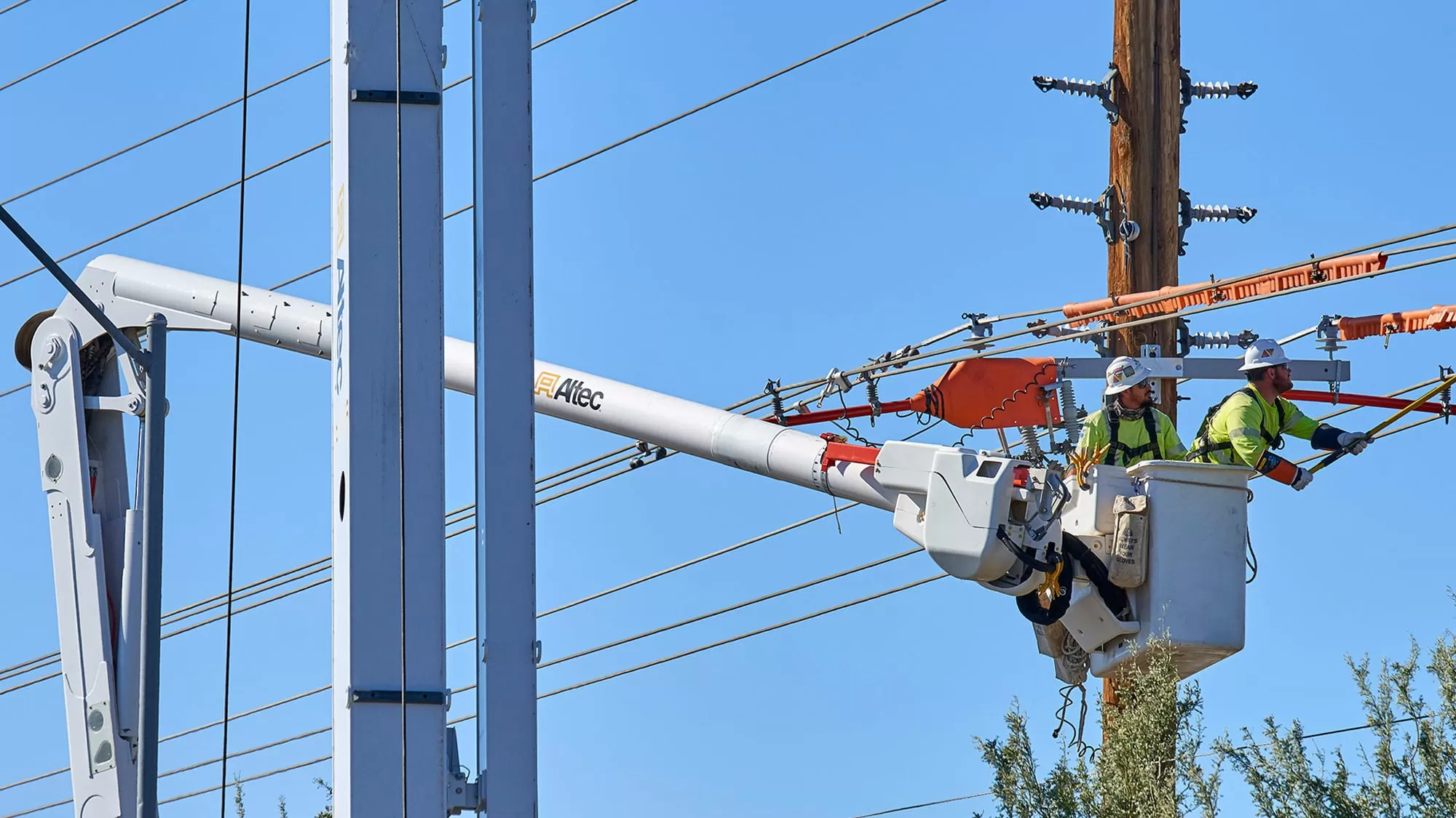 Two electrical workers in a bucket truck repairing a line.