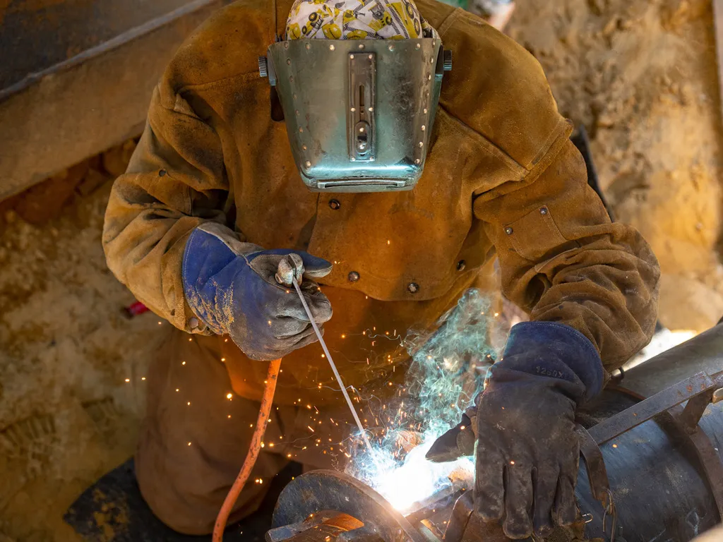 Welder in full gear working on pipe