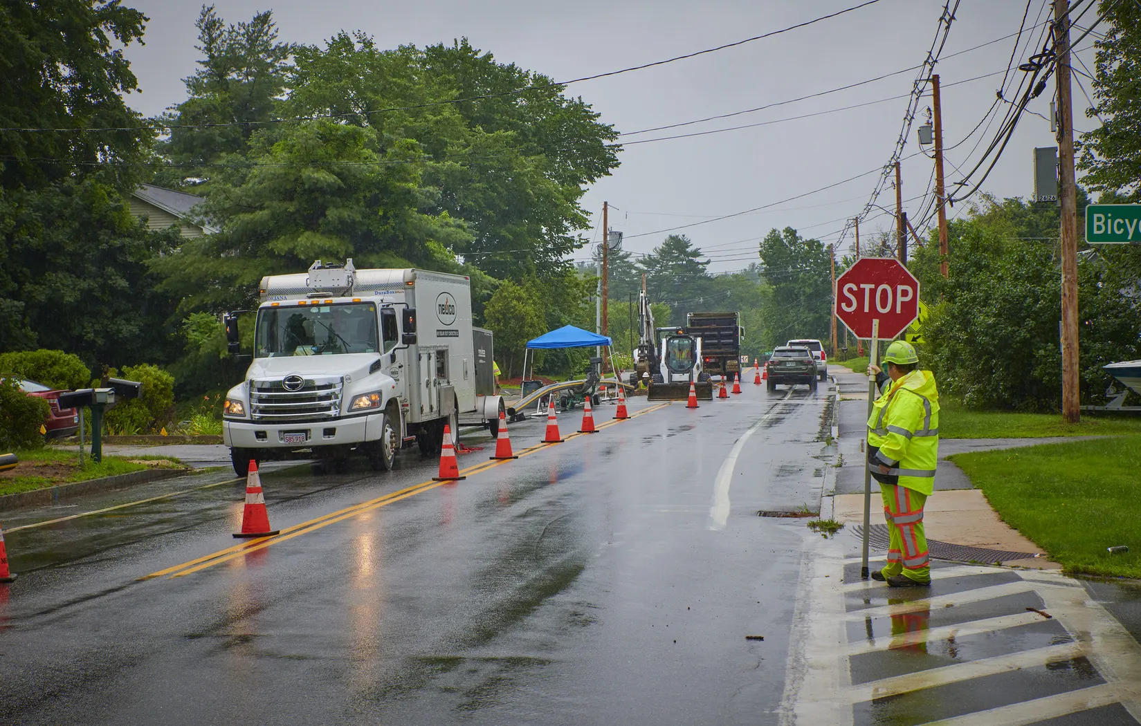 a man standing with a stop sign to direct traffic on a rainy day